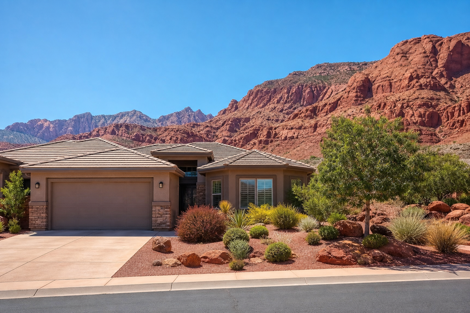 A beautiful modern home exterior with stunning Southern Utah red rock landscape in the background under a bright sunny sky.